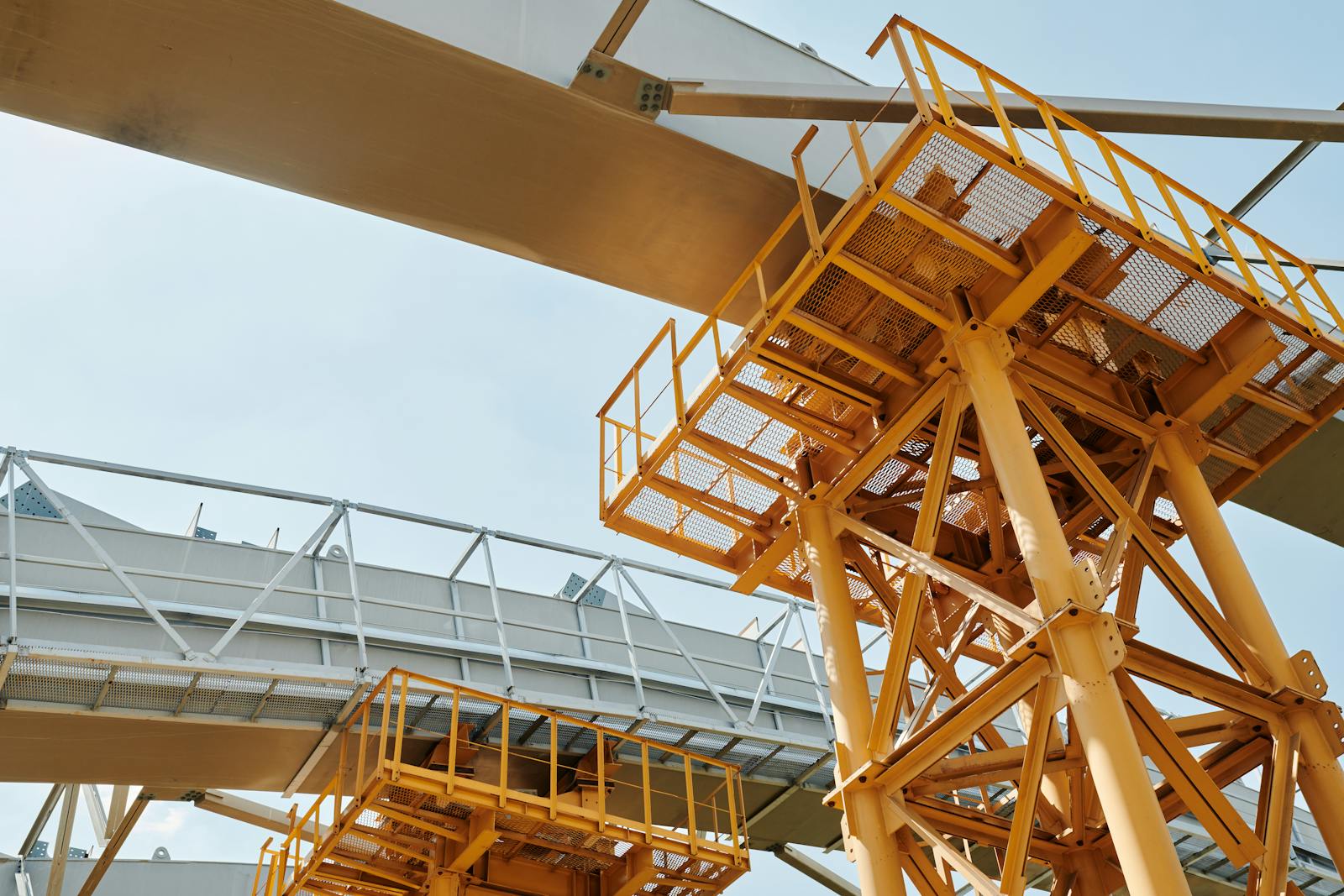 Yellow scaffolding structure with metal framework against clear sky.